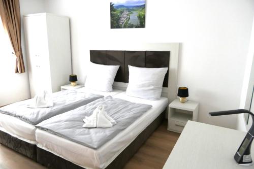 a bedroom with a large bed with white sheets at Hotel Briedeler Haus in Briedel