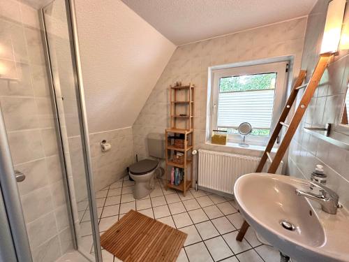 a bathroom with a sink and a shower and a toilet at Sky & Sand SPO Sonnentanz I Strandnah, Boxspringbetten, Waschmaschine, Direkt am Leuchtturm in Ording