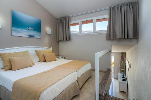 a bedroom with a large bed and windows at Apartamentos Punta Marina by LIVVO in Morro del Jable