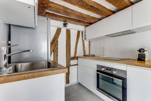 une cuisine avec des armoires blanches et un évier dans l'établissement Le princier - Charmant & proche Jardin luxembourg, à Paris