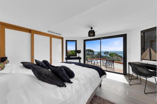 - une chambre dotée d'un lit blanc avec des oreillers et un piano dans l'établissement Villa Grande Vue, aux Issambres