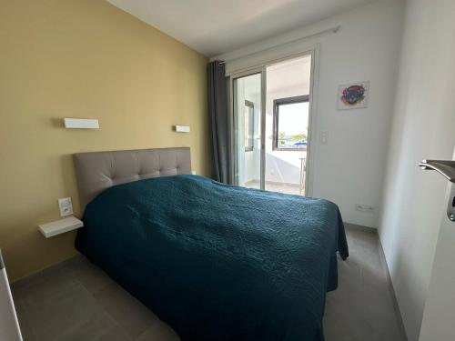 une chambre avec un lit avec une couverture bleue dans l'établissement Village naturiste - Port-Vénus - Villa les pieds dans l'eau, au Cap d'Agde