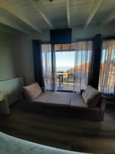 a living room with a couch and a large window at Ktima Faki, Olympus Mountain Accommodation & Retreat in Litochoro