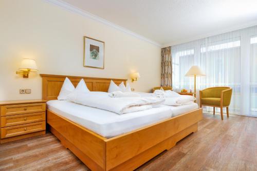 a bedroom with a large bed with white sheets at Hotel Bayerischer Hof in Bad Füssing