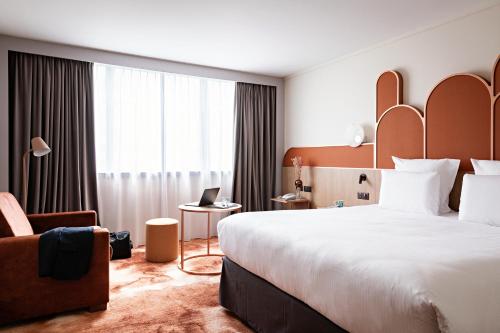 una habitación de hotel con una cama grande y una silla en Pullman Paris Centre - Bercy en París