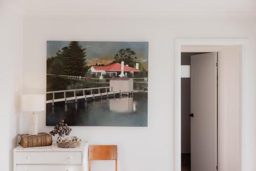 a painting of a pier on a white wall at Riverside Retreat in Orford in Orford