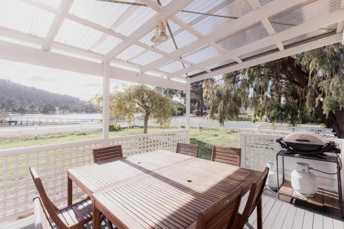 a wooden table and chairs on a patio with a grill at Riverside Retreat in Orford in Orford