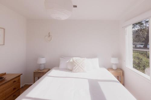 a white bedroom with a bed and a window at Riverside Retreat in Orford in Orford
