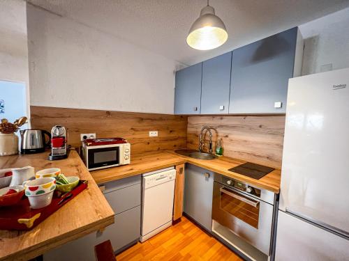 une cuisine avec des placards bleus et un comptoir en bois dans l'établissement Lucia - Proche mer, Balcon, Clim - by TGB, à Ajaccio