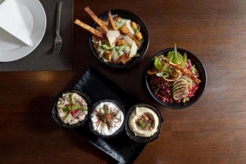 four bowls of food on a wooden table at O Beach Hotel & Resort in Sowayma