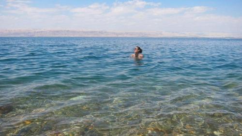 a woman standing in the water in the ocean at O Beach Hotel & Resort in Sowayma
