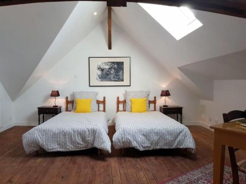 une chambre mansardée avec deux lits avec des oreillers jaunes dans l'établissement La villa Heidi, à Saint-Mars-la-Jaille