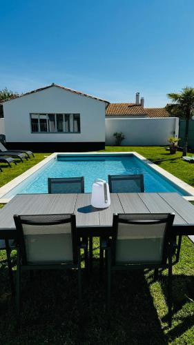 ein Tisch und Stühle neben einem Schwimmbecken in der Unterkunft Villa Marcus in Sainte-Marie-de-Ré