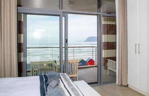 a bedroom with a balcony with a view of the ocean at Surfers Penthouse in Muizenberg