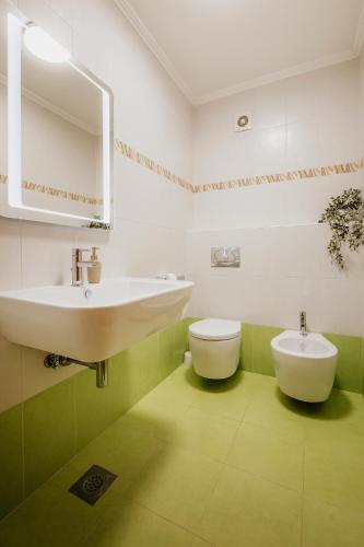 a green and white bathroom with a sink and a toilet at Supreme Apartment Bliss in Umag