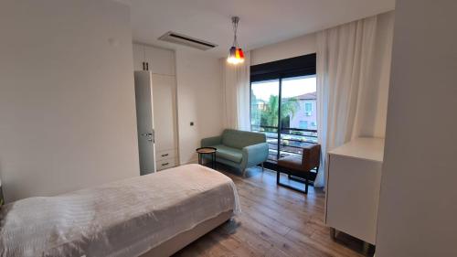 a bedroom with a bed and a chair and a window at Уютная вилла в Чамьюва in Kemer