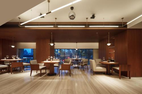 a dining room with tables and chairs and windows at Maxx by Steigenberger on the Bund Shanghai in Shanghai