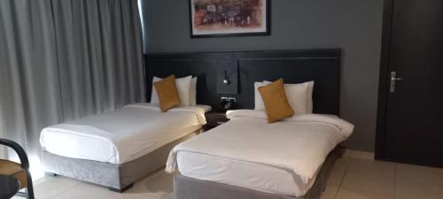 two beds in a hotel room with white and yellow pillows at O Beach Hotel & Resort in Sowayma