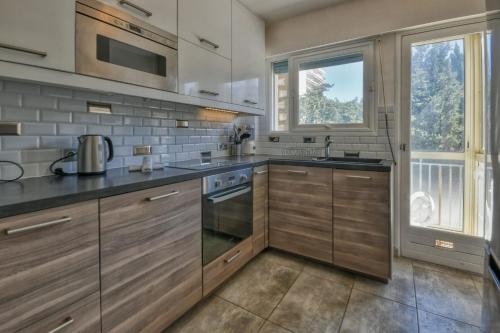 une cuisine avec des placards en bois et une grande fenêtre dans l'établissement LA ROSERAIE for 6 By Sunset Riviera Holidays, à Antibes