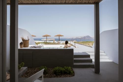 a woman sitting in a tub on the balcony of a house at Coco-Mat Hotel Santorini in Akrotiri