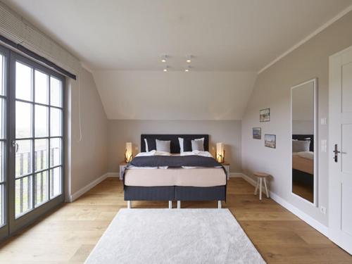 ein Schlafzimmer mit einem Bett und einem großen Fenster in der Unterkunft Reetland am Meer - Ihre Superior Reetdachvilla E28 - Zwei Schlafzimmer, Kamin & pure Wohlfühlatmosphäre in Dranske