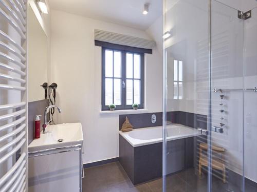 ein Badezimmer mit Badewanne, Waschbecken und Dusche in der Unterkunft Reetland am Meer - Ihre Superior Reetdachvilla E28 - Zwei Schlafzimmer, Kamin & pure Wohlfühlatmosphäre in Dranske