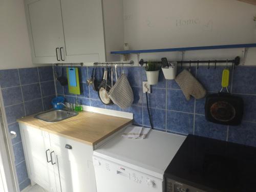 une cuisine avec des placards blancs et du carrelage bleu sur le mur. dans l'établissement Luna Beach Apartment, à Novalja