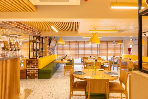 um restaurante com mesas e cadeiras de madeira e paredes amarelas em Bloom Hub I Western Highway em Mumbai