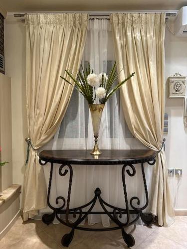 a vase with flowers on a table in front of a window at Altera Vita in Agía Zóni