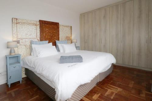 1 dormitorio con 1 cama blanca grande y mesita de noche en South Surf Apartment, en Muizenberg