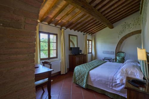 a bedroom with a bed and a desk and a window at Villa Curina Resort in Castelnuovo Berardenga