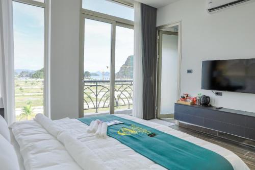 a bedroom with a large white bed with a large window at Ao Tien Harbour Boutique Hotel in Hà Cái