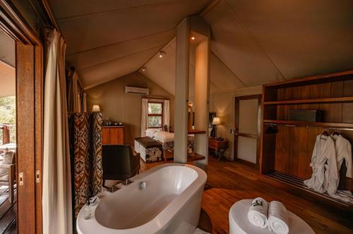 a large bathroom with a tub and a bedroom at Kapama Buffalo Camp in Kapama Private Game Reserve