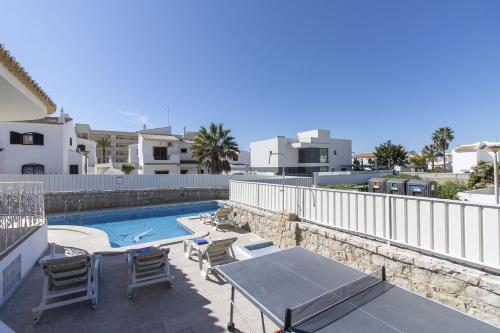 a patio with tables and chairs next to a swimming pool at Villa Brisa do Mar in Galé