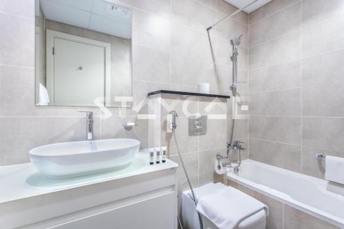 a bathroom with a sink and a tub and a toilet at Staycae Holiday Homes - Carson Towers in Dubai