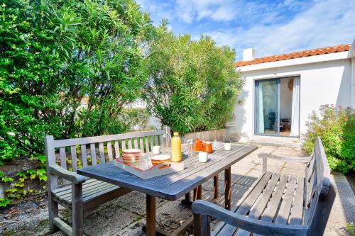 une table en bois avec deux chaises et une table avec de la nourriture. dans l'établissement En plein centre de Noirmoutier en l ile - Maison pour 6, à Noirmoutier-en-l'lle