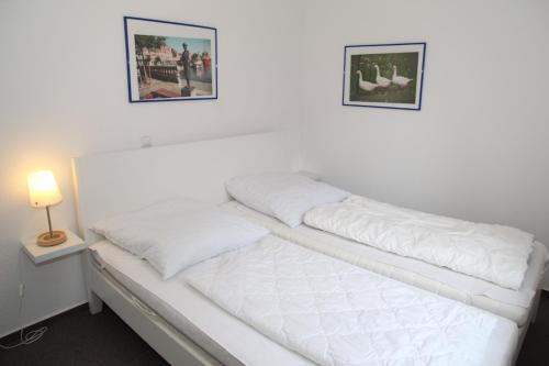 a white bed with two pillows on top of it at Ebbe in Norden