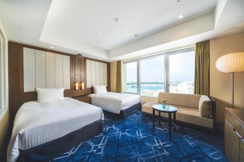 那覇市にあるリーガロイヤルグラン沖縄のベッド2台とソファが備わるホテルルームです。
