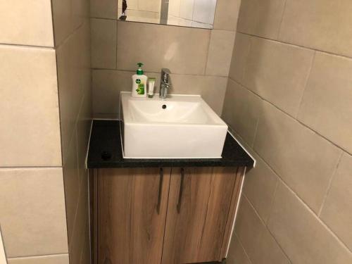 Un baño con un lavabo blanco y un espejo. en Exquisite Home In Sandton with Pool and Inverter, en Johannesburgo