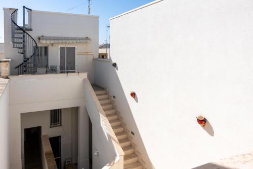 two people on the side of a white building with stairs at Seasons Home San Foca in San Foca