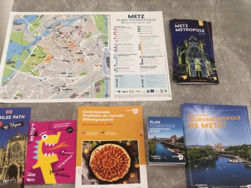 un tas de livres posés sur une table avec une carte dans l'établissement Superbe Appartement tout équipé, Le nid d'Eva à Metz Gare, Parking privé, Balcon, F2, 50m2, 3p, à Metz