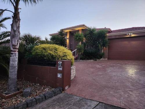 a house with a garage and a palm tree at Home in Greenvale, Victoria in Greenvale