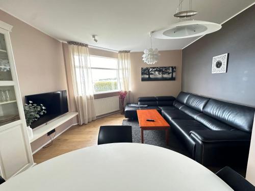 a living room with a black leather couch and a table at Apartment in Huldubraut in Kópavogur - Birta Rentals in Reykjavík