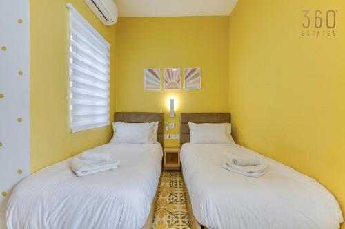 two twin beds in a room with yellow walls at Stunning Traditional 3BR Townhouse in Siggiewi by 360 Estates in Siġġiewi