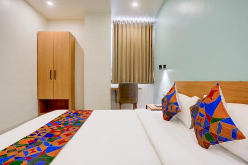 a bedroom with a large white bed with colorful pillows at FabHotel Prime Ace II - Near Jupiter Hospital in Vadodara