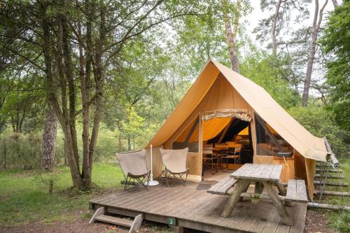 a tent with a table and chairs on a wooden deck at Huttopia Rambouillet in Rambouillet