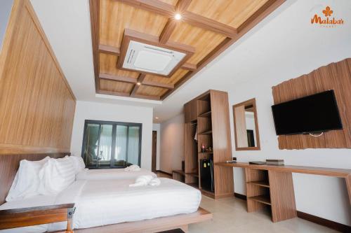 a bedroom with a large bed with a tv and a bed at Malabar Pool Villa Phuket in Phuket Town