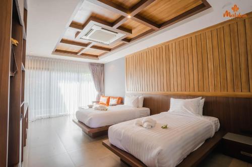 a hotel room with two beds and a window at Malabar Pool Villa Phuket in Phuket Town