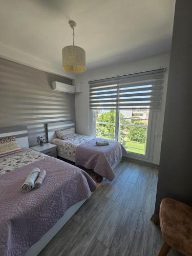 a bedroom with two beds and a large window at Spacious Beachfront Two-Bedroom Apartment in Caesar Beach in Boghaz