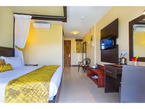 a bedroom with a bed and a desk and a television at Wigot Gardens Hotel in Kisumu